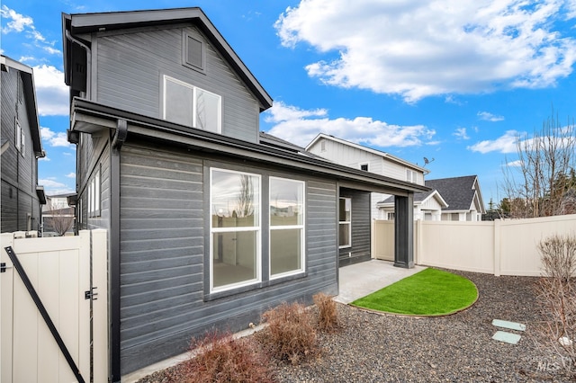 rear view of property featuring a patio area, a gate, and fence