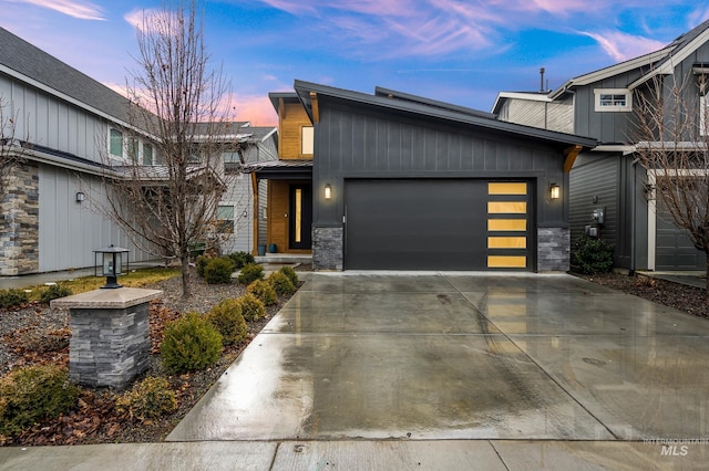 view of front of home featuring stone siding, concrete driveway, and a garage