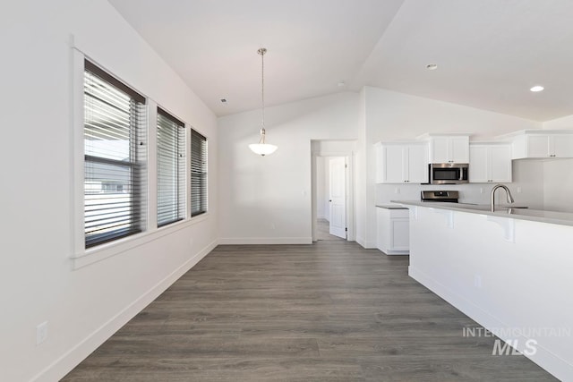 kitchen with lofted ceiling, a healthy amount of sunlight, white cabinets, and decorative light fixtures