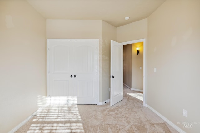 unfurnished bedroom featuring light colored carpet and a closet