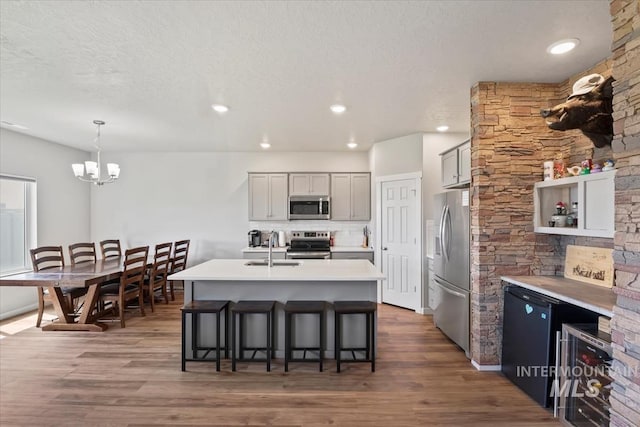 5006 Clearfield St, Caldwell, ID 83605 - kitchen with stainless steel appliances, a sink, wood finished floors, a breakfast bar area, and a textured ceiling