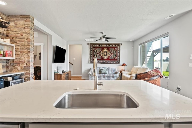 5006 Clearfield St, Caldwell, ID 83605 - kitchen featuring a sink, open floor plan, ceiling fan, light stone counters, and a textured ceiling