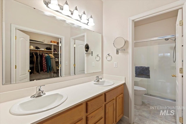 bathroom featuring tile patterned flooring, vanity, a shower with shower door, and toilet