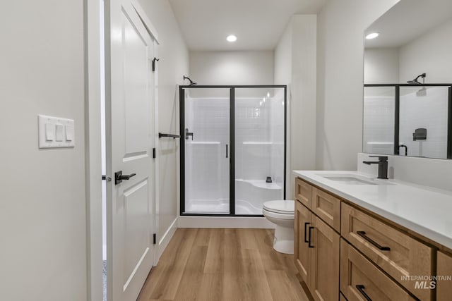 bathroom with hardwood / wood-style flooring, vanity, an enclosed shower, and toilet