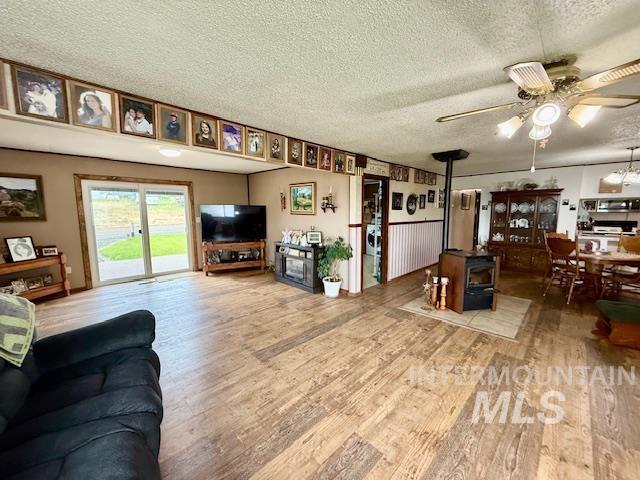 908 Pine St, Anatone, WA 99401 - living room with a wood stove, ceiling fan, wood finished floors, and a textured ceiling