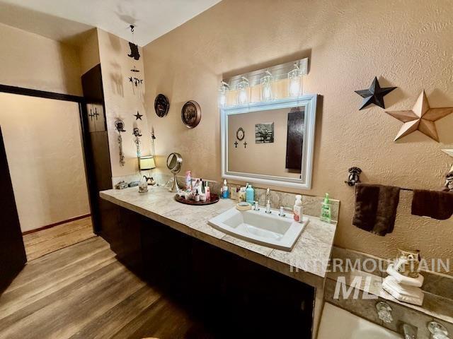908 Pine St, Anatone, WA 99401 - full bathroom featuring wood finished floors, vanity, and a textured wall