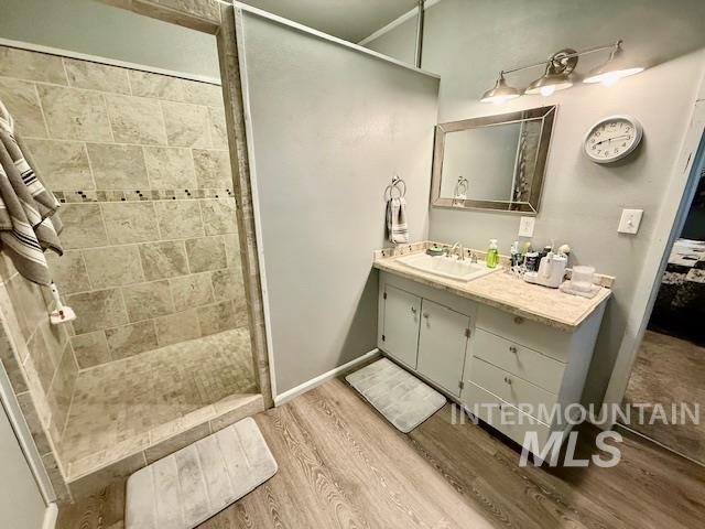908 Pine St, Anatone, WA 99401 - bathroom featuring vanity, tiled shower, and wood finished floors