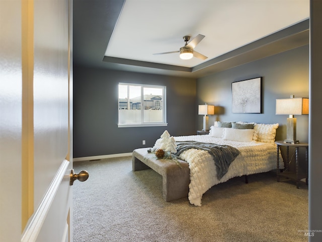 bedroom with carpet floors, ceiling fan, and a tray ceiling