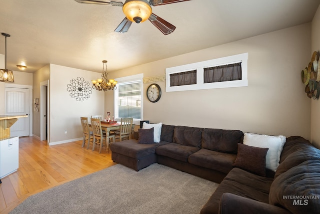 living room with ceiling fan with notable chandelier and light hardwood / wood-style flooring