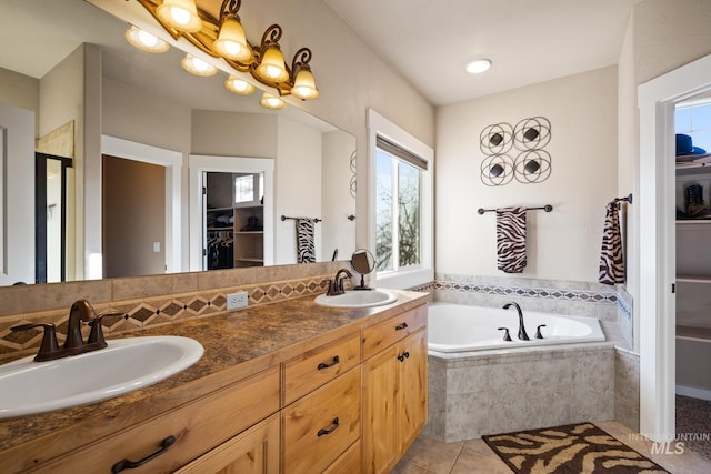 bathroom with tile patterned flooring, vanity, a relaxing tiled tub, and a chandelier