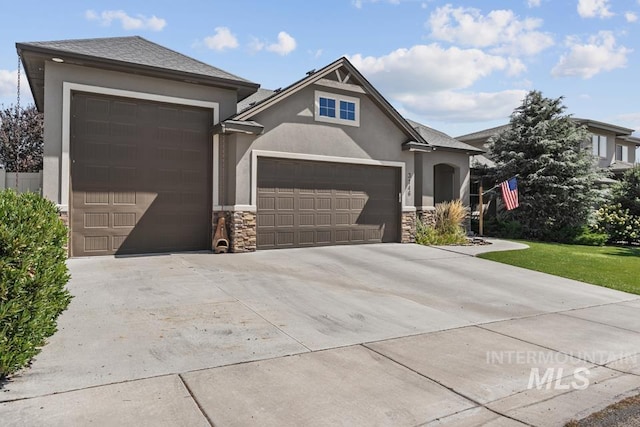 view of front facade with stone siding, driveway, an attached garage, and stucco siding