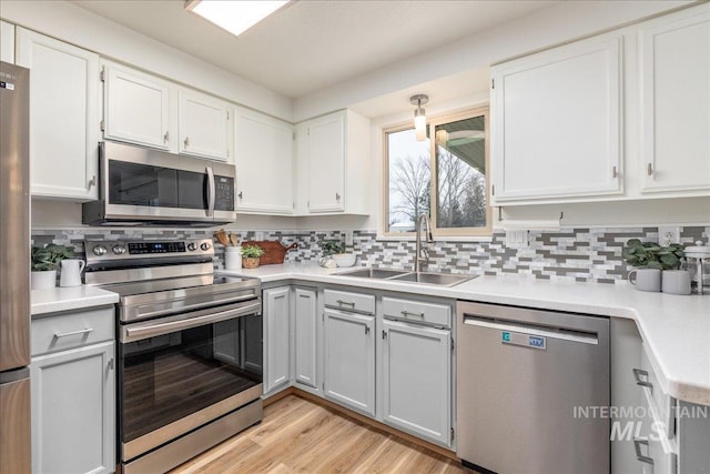 kitchen with tasteful backsplash, sink, white cabinets, and appliances with stainless steel finishes