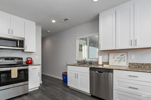 kitchen featuring visible vents, a sink, stone counters, and appliances with stainless steel finishes