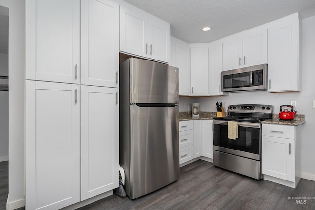 kitchen featuring stone countertops, white cabinetry, appliances with stainless steel finishes, and dark wood-style flooring