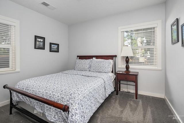 bedroom with baseboards, dark colored carpet, and visible vents