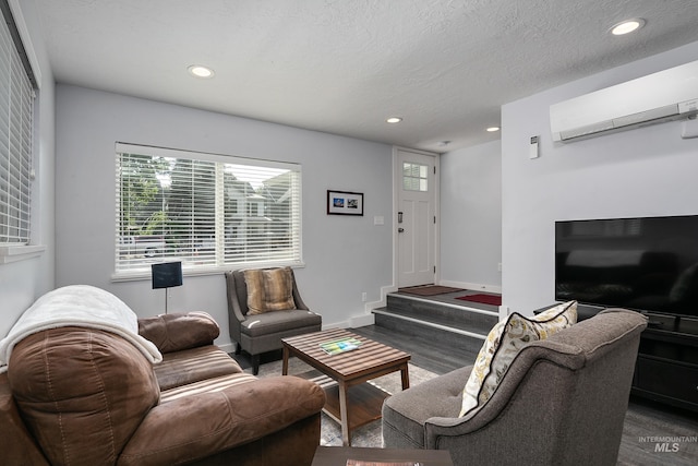 living room featuring wood finished floors, a textured ceiling, baseboards, an AC wall unit, and recessed lighting