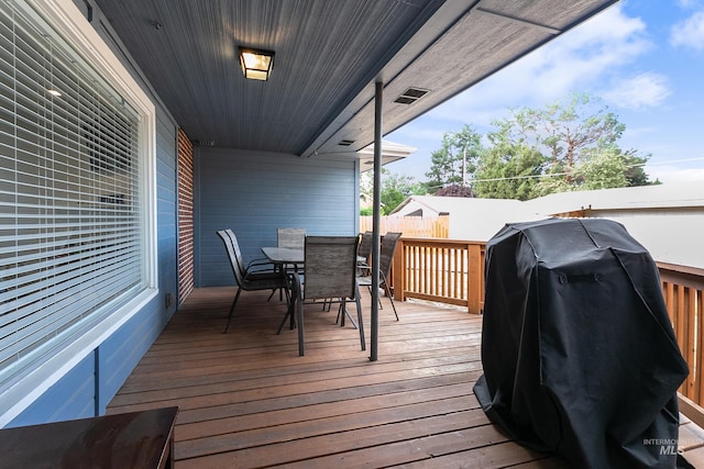 deck featuring outdoor dining space, area for grilling, and fence
