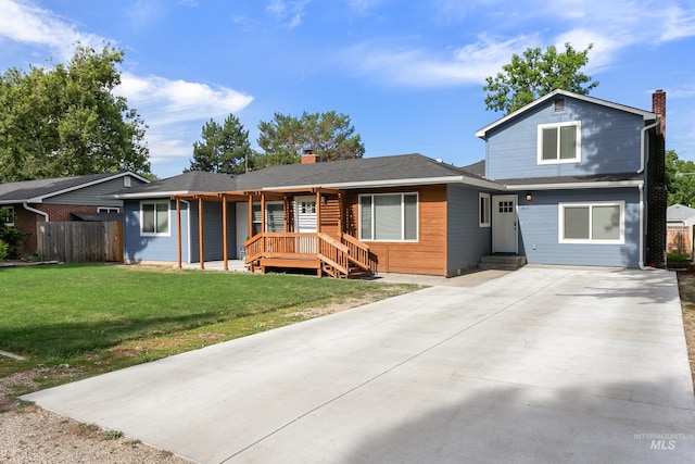 view of front of property with driveway, a chimney, fence, and a front yard
