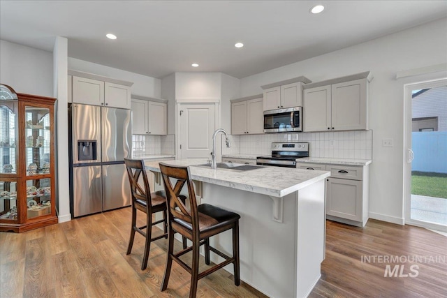 1275 Terra Ave, Twin Falls, ID 83301 - kitchen with appliances with stainless steel finishes, light wood-style floors, backsplash, a center island with sink, and recessed lighting