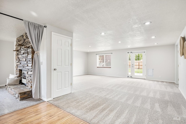 5457 S Oseola Pl, Boise, ID 83709 - unfurnished living room with a textured ceiling, light carpet, light wood finished floors, a stone fireplace, and recessed lighting