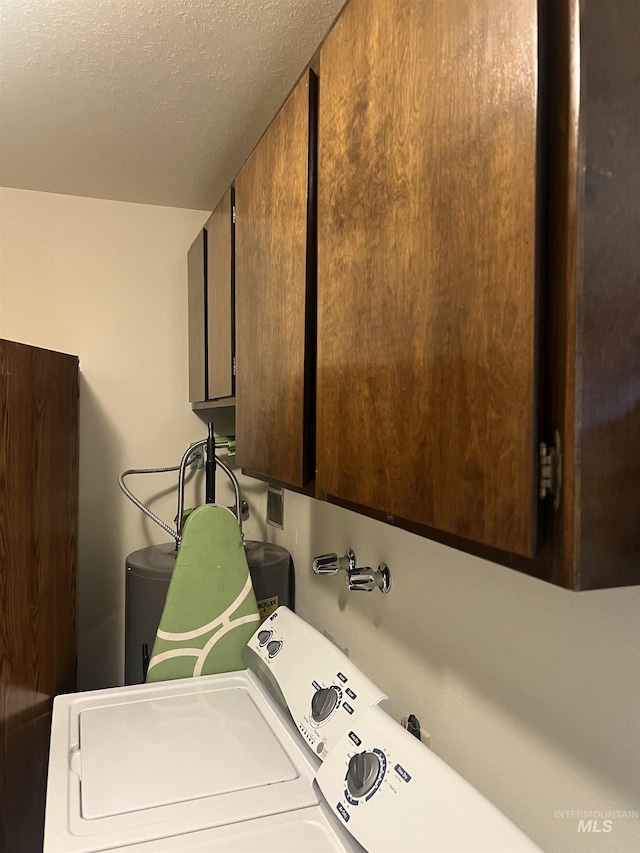 laundry room with a textured ceiling, washing machine and clothes dryer, and cabinet space