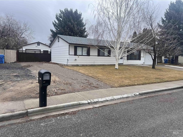 ranch-style home with driveway, a garage, fence, and a front yard