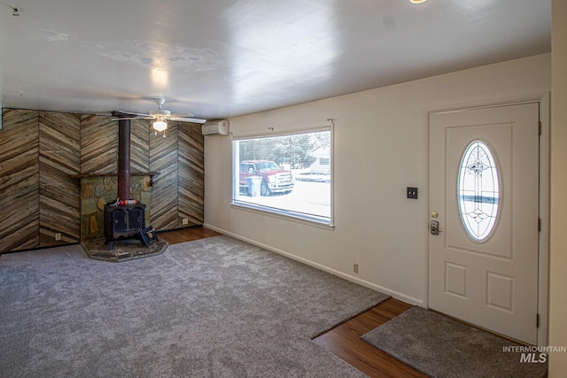 foyer featuring a wood stove, plenty of natural light, baseboards, and a wall mounted AC