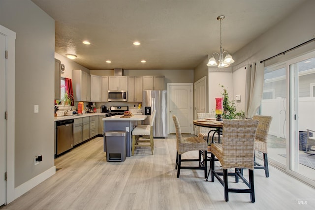 kitchen featuring gray cabinetry, hanging light fixtures, stainless steel appliances, a kitchen breakfast bar, and a kitchen island