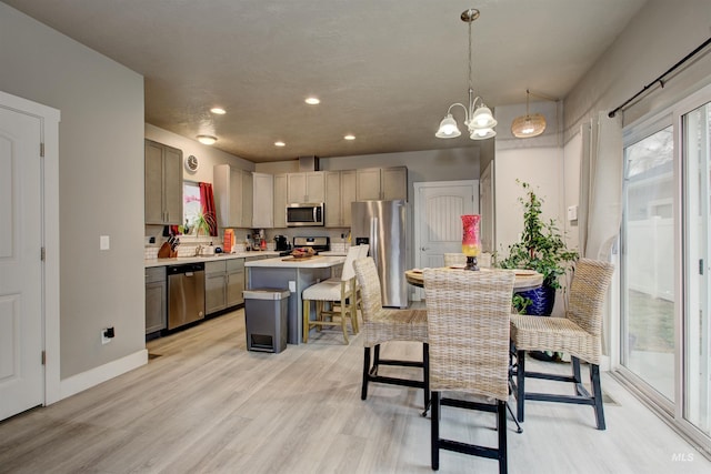 kitchen with a breakfast bar, a center island, gray cabinets, pendant lighting, and stainless steel appliances