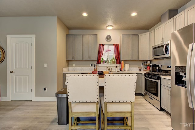 kitchen featuring sink, a breakfast bar area, a center island, light hardwood / wood-style flooring, and stainless steel appliances