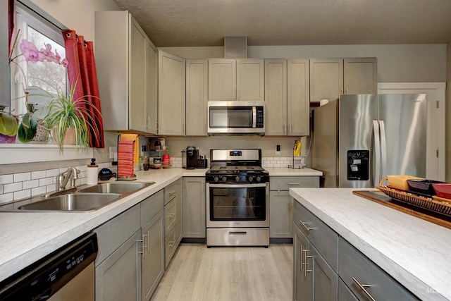 kitchen featuring appliances with stainless steel finishes, sink, light hardwood / wood-style flooring, and gray cabinetry