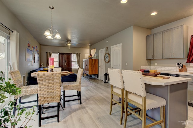 dining room featuring ceiling fan with notable chandelier and light hardwood / wood-style flooring