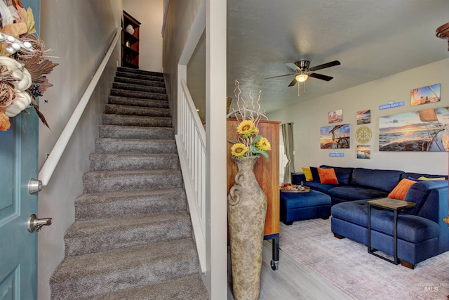 stairs with wood-type flooring and ceiling fan