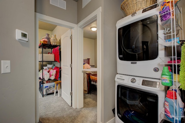 clothes washing area with stacked washer and dryer and carpet flooring