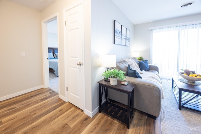 living area with baseboards, wood finished floors, and visible vents