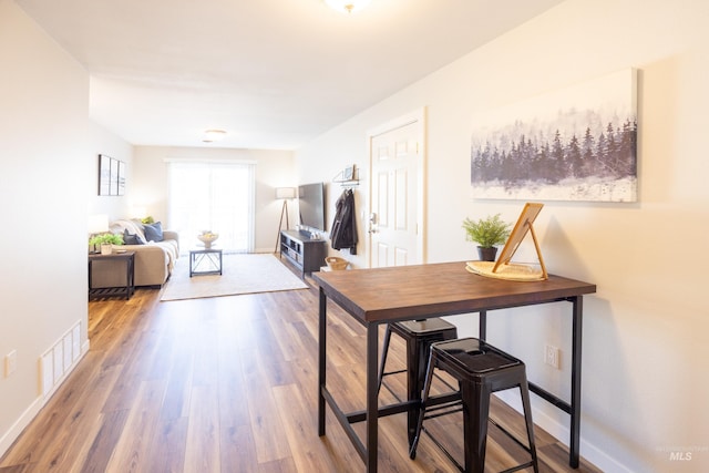 dining area with wood finished floors, visible vents, and baseboards