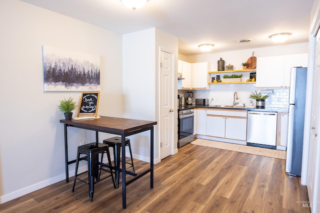 kitchen featuring wood finished floors, a sink, white cabinetry, and appliances with stainless steel finishes