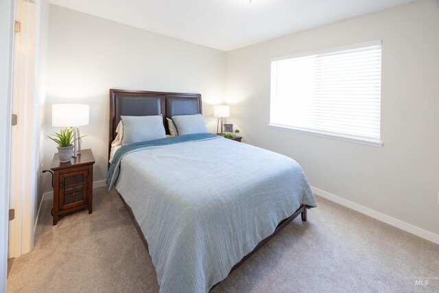bedroom with baseboards and light colored carpet