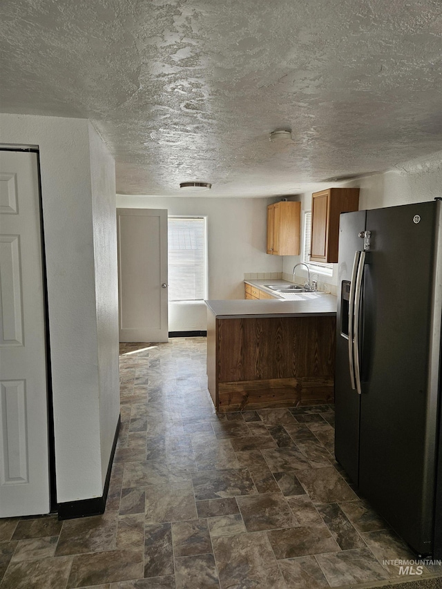 407 E Freeport St, Caldwell, ID 83605 - kitchen featuring stainless steel fridge with ice dispenser, light countertops, brown cabinetry, a peninsula, and a textured ceiling