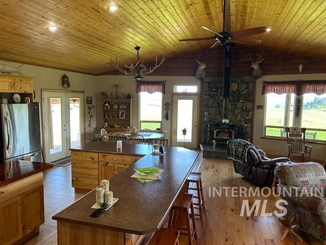 1621 Doumecq Rd, Cottonwood, ID 83522 - kitchen featuring freestanding refrigerator, vaulted ceiling, wooden ceiling, ceiling fan, and a wood stove