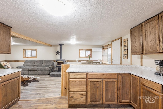 kitchen with a wall unit AC, a healthy amount of sunlight, open floor plan, and a peninsula