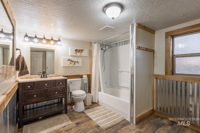 bathroom with a textured ceiling, toilet, wood finished floors, and shower / bath combination with curtain