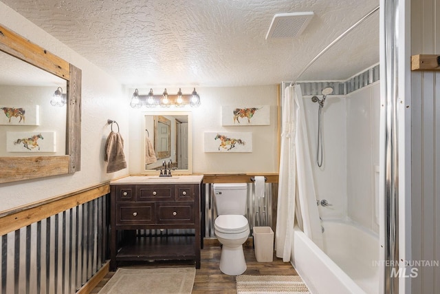 full bath featuring wood finished floors, visible vents, shower / bath combo, a textured ceiling, and toilet