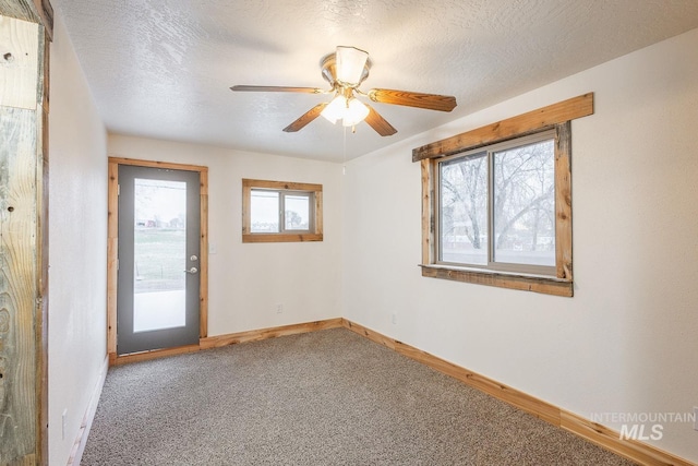 carpeted spare room featuring baseboards, a textured ceiling, and ceiling fan