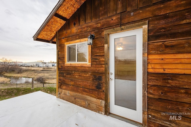 view of exterior entry with a patio and board and batten siding