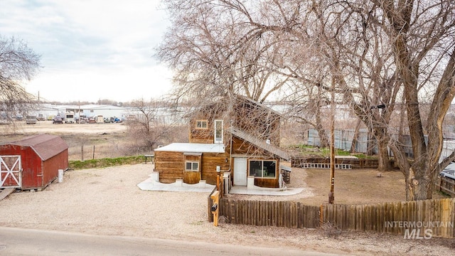 view of front of property with an outdoor structure, a shed, and fence