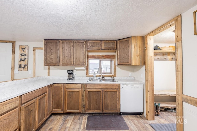 kitchen with dishwasher, light countertops, light wood-type flooring, and a sink