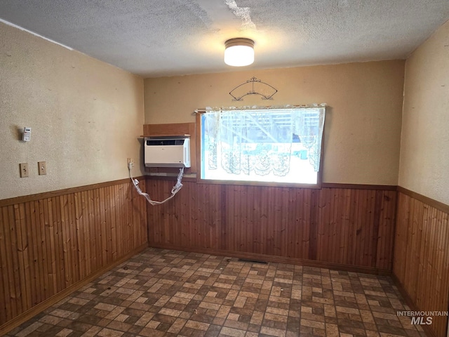 495 1st St E, Huntington, OR 97907 - empty room with wainscoting, a textured ceiling, wooden walls, brick patterned floors, and a wall mounted air conditioner