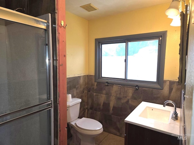 495 1st St E, Huntington, OR 97907 - bathroom featuring tile walls, toilet, vanity, tile patterned flooring, and a shower with shower door