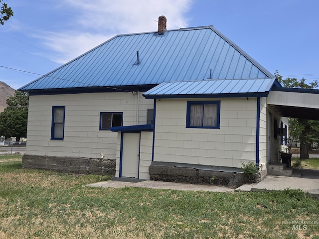 495 1st St E, Huntington, OR 97907 - back of property featuring a standing seam roof, a chimney, a lawn, and metal roof